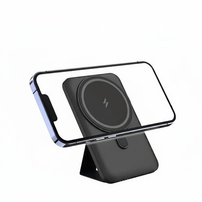 Essential Selects black magnetic wireless power bank with foldable stand attached to an iPhone for hands-free viewing
