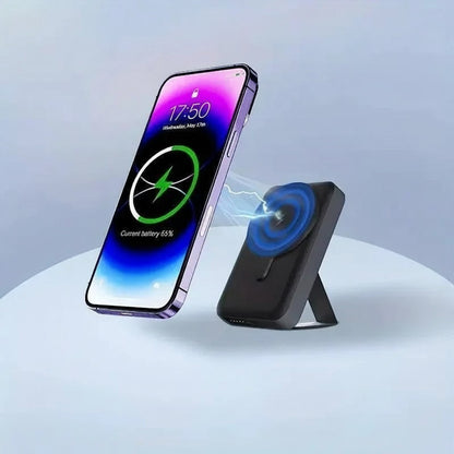 Essential Selects 10000mAh magnetic wireless power bank with foldable stand charging an iPhone on a light blue surface