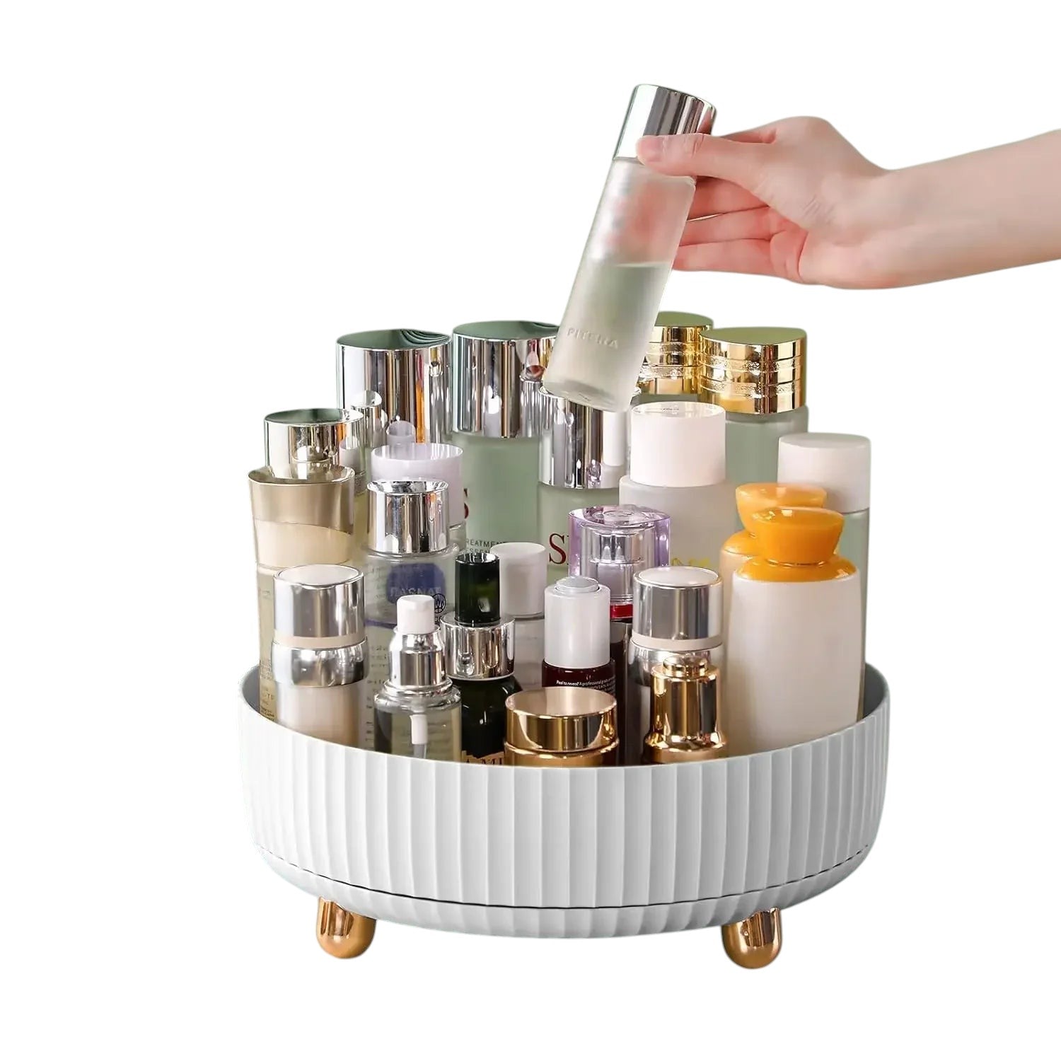 Essential Selects white rotating makeup organizer on a green surface holding various skincare bottles and cosmetics