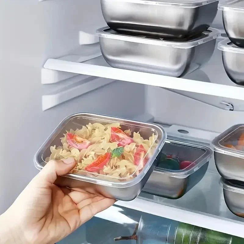 Essential Selects stainless steel meal prep containers with clear lids, stacked inside a refrigerator.